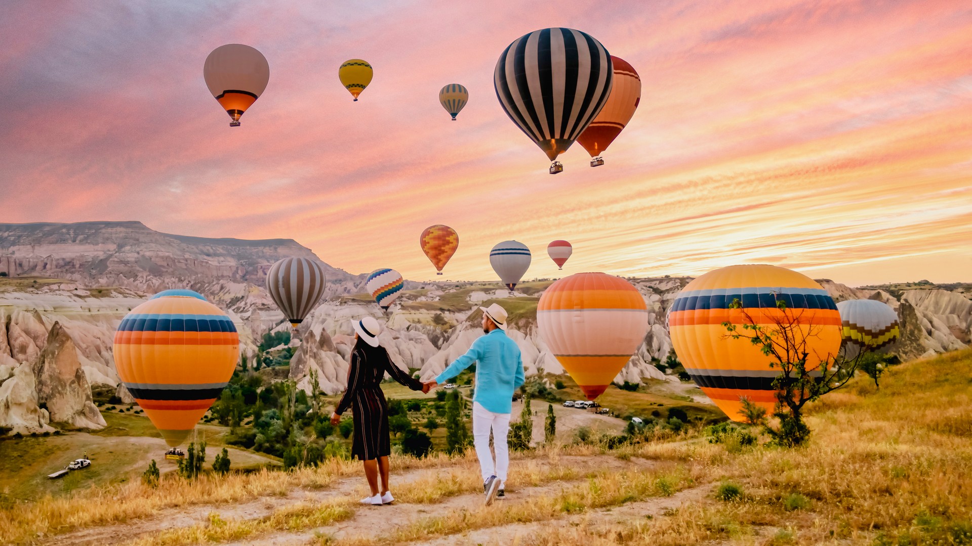 Cappadocia Turkey during sunrise, couple mid age men and woman on vacation in the hills of Goreme Capadocia Turkey, men and woman looking sunrsise with hot air balloons in Cappadocia